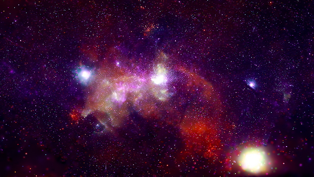 Adapted from link in toot: This image is titled Galactic Center. Here, the center of the Milky Way galaxy resembles a pink, orange, red, and purple cloud, dotted with several brilliant orbs of light. Surrounding the cloud is a dense field of purple, orange, red, and pale blue specks that entirely blankets the sky. In this image, orange, blue, and purple represent X-ray light from the Chandra X-ray Observatory.