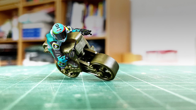 A photoshop composition of a moto gp rider on a "bike", which is actually a VVS bogey from a plastic model kit of a Sherman tank, which kind of looks like a bike...