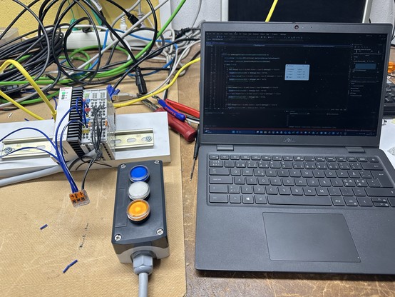 A laptop, a PLC and a box with buttons and lamps.