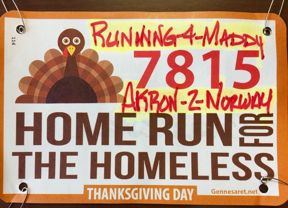 Color image of a runner's bib for the 32nd Annual Homerun for the Homeless Thanksgiving Day 4-mile run in Akron, Ohio, USA. Image shows a graphic turkey design on the left, the runner's number, 7815, on the right in red, and the name of the run, HOME RUN FOR THE HOMELESS in brown block letters.