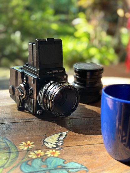 A Bronica SQ-A medium format film camera sits on a table with a coffee mug.