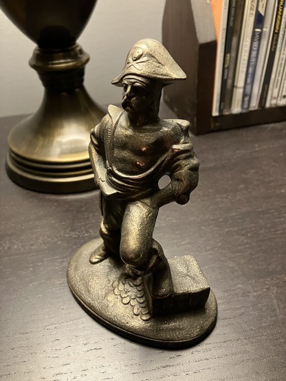 Same pirate book end from a different angle. He is standing on a cabinet top with a table lamp shining from above.