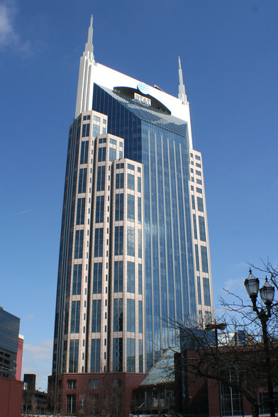 a photo of a futuristic-looking building, the windows are blue, at the top there are two points on either side of it, at&t in the middle of the top , the sky is blue