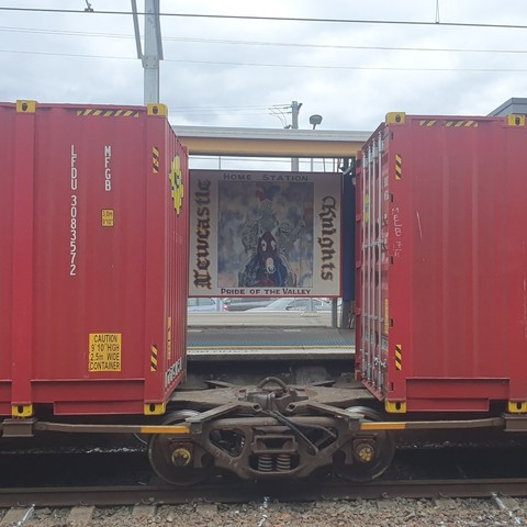 A Newcastle knights painting between two freight rail containers