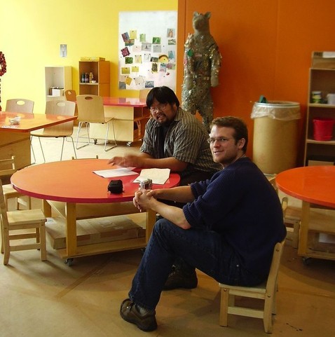 pedagogy and andragogy: photograph of two men sitting on tiny chairs in a nursery school