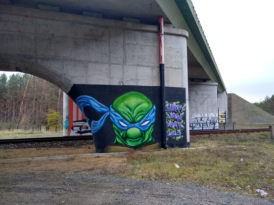 A shot parallel to the viaduct. A support is visible in front, on which a head of a ninja turtle is visible, though it looks elderly rather than teenage. On the right, the inscription says "Happy New Year 2023".