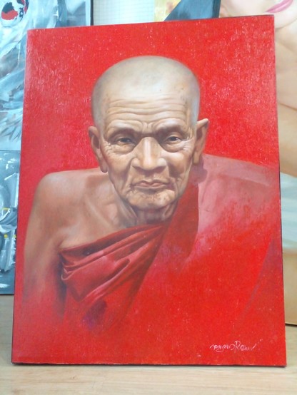 a painting of an elderly monk named Luang Phor Tuad, he has no hair, he is wearing a orange-red robe, the background of the painting is the same red color as his robe, he looks at the viewer
