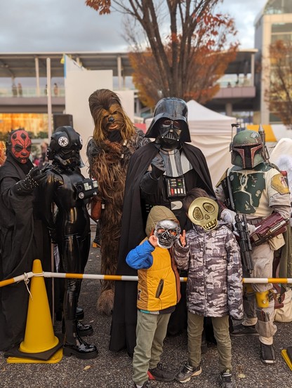 Kids posing with Star Wars cosplay characters, L to R: Darth Maul, Tie Fighter Pilot, Chewbacca, Darth Vader, Boba Fett.