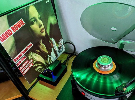 LP playing on turntable under green tinted light. Album cover on left side of image, turntable on right.
