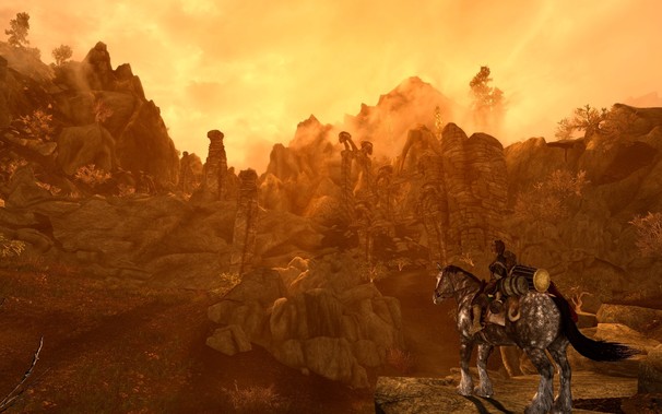 A rich orange sunset. In the background there are stone ruins lining a mountainside. In the foreground is a female cat-like humanoid called a Khajiit riding a horse. The horse has musical instruments and bags and wine bottles hanging from its saddle