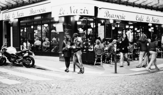 Couple devant la terrasse d'un café, noir et blanc.