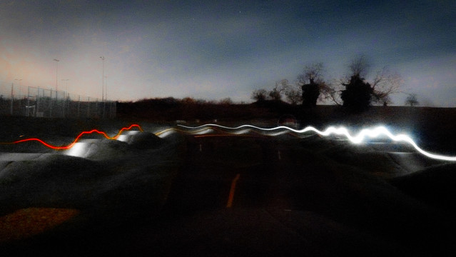 A pump track at dusk using long exposure to show a light trail following the shape of the track.