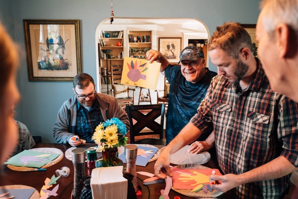A family sits around a table making turkeys out of construction paper