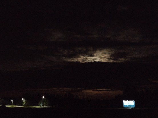 Nightly rural landscape with streetlights and an eerie glow behind the clouds