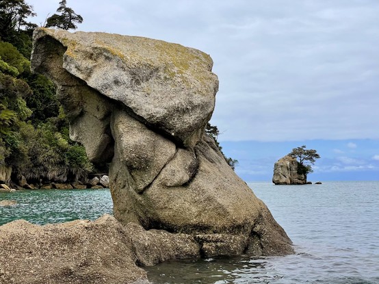 Some may see an obvious face in an offshore rock, looking to left with chin , ear, nose, eye & head covering; another offshore rock with tree on top in right of frame