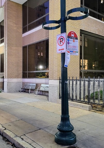 A photo of the Euclid @ BJC bus stop in St. Louis, Missouri, where two permanent benches have been installed in the building alcove in the background of the photo. The benches use hostile architecture and have armrests in the center to discourage their use for sleeping.
