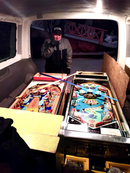 View inside a van, with two pinball machines on board and yours truly freezing and looking suffering.