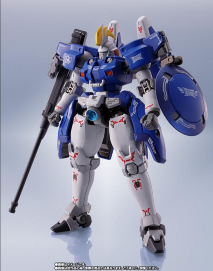 a photo of a model of a gundam war mechanical suit, the shoulders, chest, and side plates on thighs, and shield are blue, the rest white, some black, a yellow crest on his head, a long black cannon in one arm, his round shield on the other