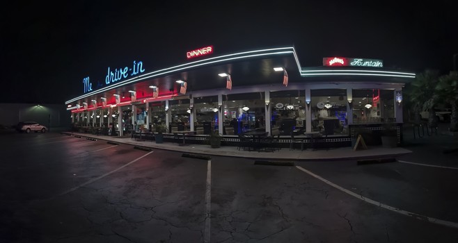 A nine-frame nighttime panoramic photograph of Mel's Drive-in on Geary Boulevard in San Francisco's Richmond District. The Neon sign has a couple letters and the apostrophe that are not working, so the sign appears to read Me Drive-in.