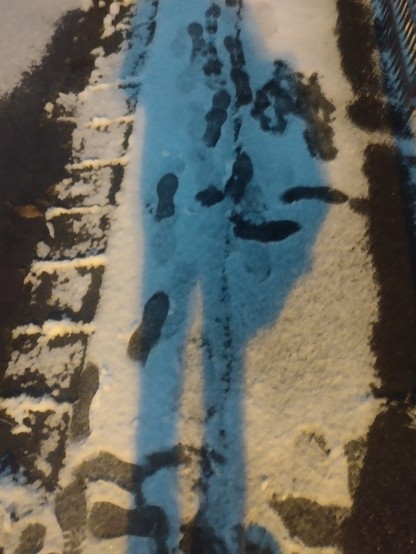 Fußspuren im Schnee auf einem Gehsteig