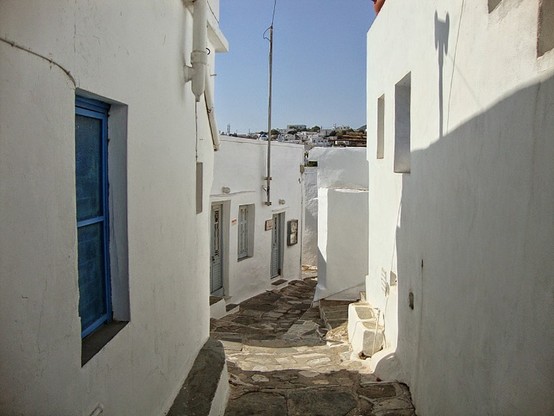 a photo of a walkway between buildings in the town, the buildings white, the sky blue
