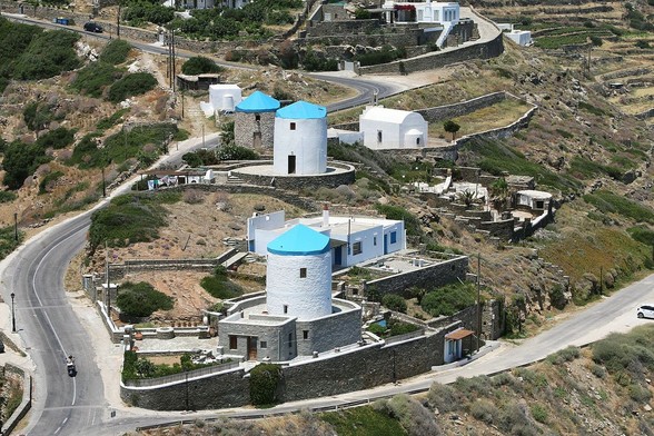 a photo of several silo-type structures with blue tops, roads curving around, old rock walls in the rolling hillside