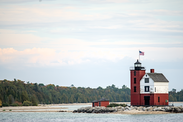 A small red and white lighthouse surrounded by water.