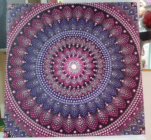 a mandala made of pink, purple, and white dots on black background