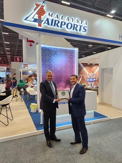 Two people holding an award at Malaysia Airports booth.