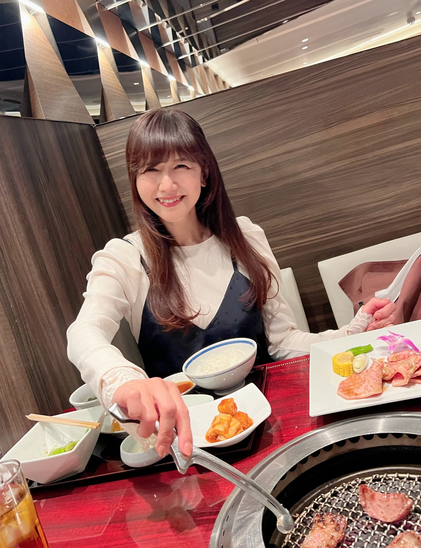 Kikuko smiling as she grills meet with plates on the table at a restaurant.