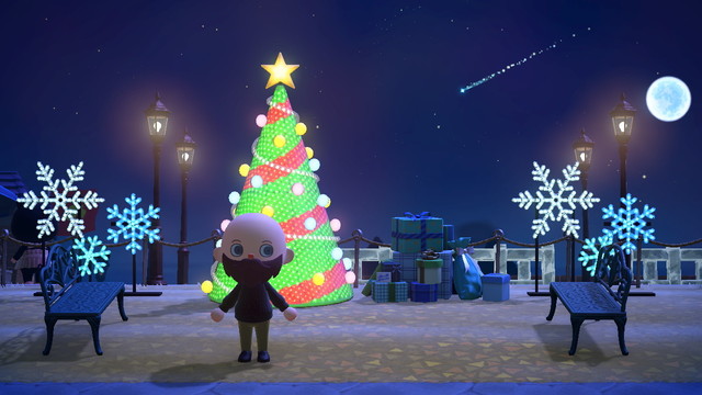 Animal Crossing: New Horizons screenshot. Set at night with a gorgeous, clear sky and a single shooting star in the background in the upper right. Light skinned, bald, bearded human villager wearing a black sweater and khakis is standing in a small rest area with two blue garden benches on either side. Along the back behind the villager is an illuminated tree and a blue pile of presents. On either side of them are snowflake lights all lit up.

Further in the background, lit streetlamps and some ice fencing can be seen.