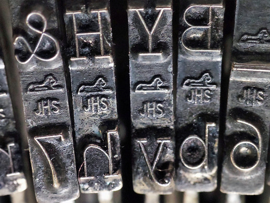 Typewriter 'slugs'. The metal reverse letters used to print on typewriters. 
There are two characters per key, lower and upper case. The photo shows the & 7, H h, Y y, B b, and underline 6 keys.  In the middle of each key is a graphic of a lion, and the letters JHS, although this is not printed.
