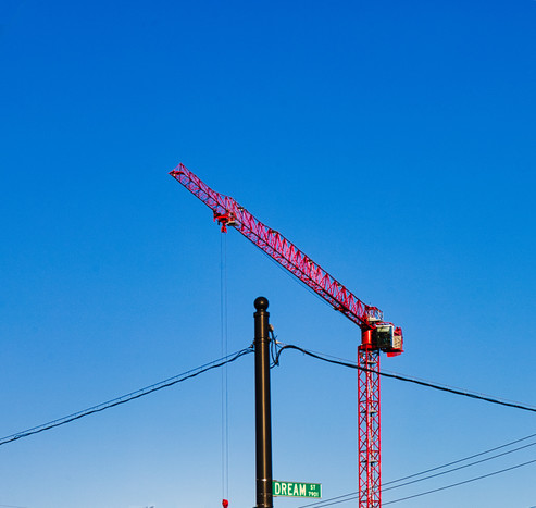 bright red construction crane, cloudless blue sky, black utility pole with street sign saying Dream