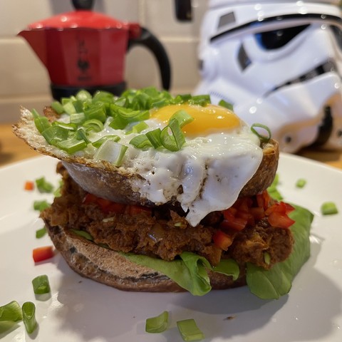 Podwójny tost, z zieloną sałatą, pastą z makreli, jajkiem sadzonym posypane szczypiorem. W tle kawiarka i hełm stormtroopera.