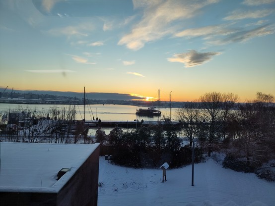 Förde in Kiel mit Sonnenaufgang und Personenfähren auf dem Wasser. Eine davon ist im Vordergrund.