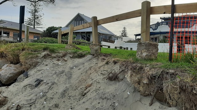 A fence in front of a beachside house once concreted into land that has collapsed has been lifted and placed above the slip.