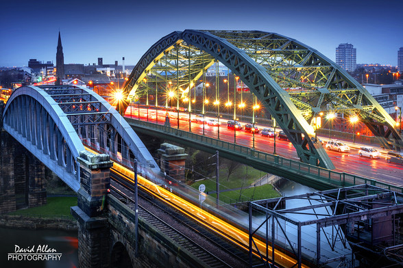 An evening long-exposure photograph showing the light trails on the two city centre bridges over the River Wear in Sunderland, North East England.