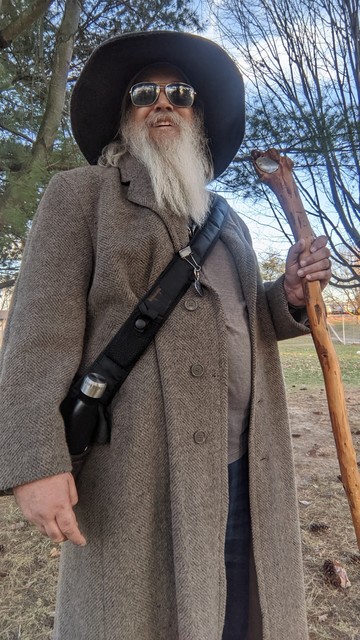 middle aged man with grey beard and gandalf style hat and staff