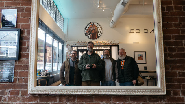 Four bearded men pose for a group selfie in a mirror