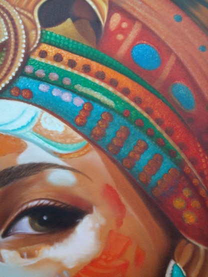 a close-up of the headress, her eye, and a section of her upper cheek . the woman has red paint on her cheeks