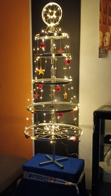Weihnachtsbaum, zusammengesetzt aus unterschiedlich groÃŸen FahrradvorderradlaufrÃ¤dern und gekÃ¼rzten SattelstÃ¼tzen, geschmÃ¼ckt mit Lichterketten, Weihnachtsbaumkugeln und Sternen.