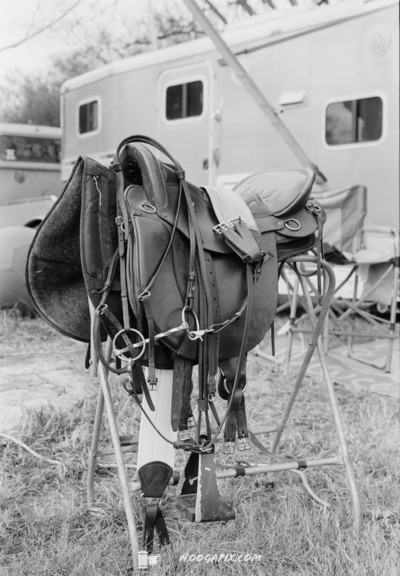 Black and white photo of a saddle in front of a trailer