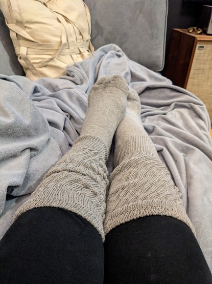 My feet in thick gray knee high socks, bunched on top of black leggings
