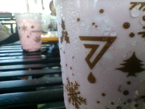 Closeup of the Sevendays' logo printed at the side of the cup, surrounded by Christmas-themed designs.