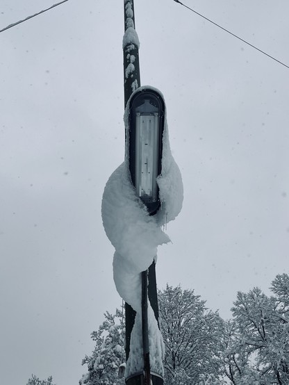 Snow on street lamp.