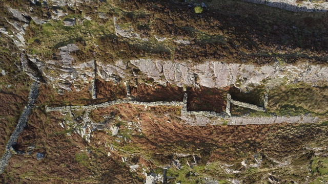 Vertical view of the 5-celled buarth (sheepfold), highlighted in low winter sunlight. It is built on a narrow ledge in the rockface.