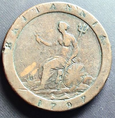 Seated figure of Britannia left, with trident and shield in left hand, olive branch in raised right hand, shield bearing Union flag resting on left, sea behind with ship on left, mint name below shield, legend above and date below on raised rim. Script: Latin Lettering: BRITANNIA SOHO 1797 Engraver: Conrad Heinrich Küchler Read more on Wikipedia
