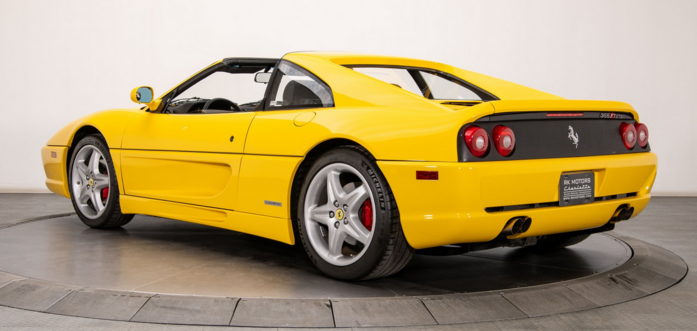 a photo of a yellow 1998 ferrari, seen from the back in a three quarter view