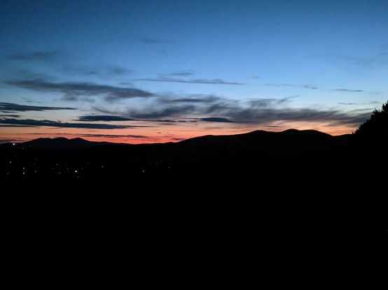 A rim of red separates the dark mountains from the deep blue sky of twilight.