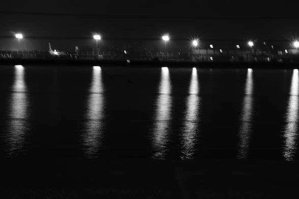 Night shot of the lights of London City Airport across the water of Royal Albert Dock - the camera was resting on a bench, set to black and white, shutter speed was something in the many seconds (aperture f11 so lots in focus from near to far) and any motion on the water was integrated into blurred light forms of the reflections of the airport lights

It was freezing cold – about 0°
